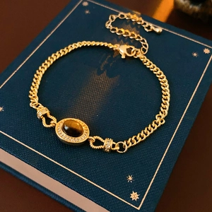 Detailed close-up of gold-plated bracelet with oval tiger eye stone and zircon accents