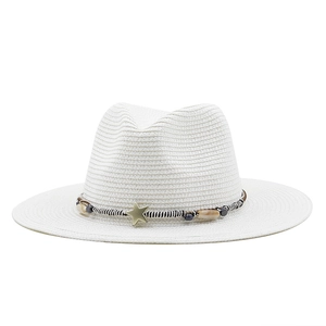 Close-up of a white straw sun hat featuring a striped cord band with a gold star charm