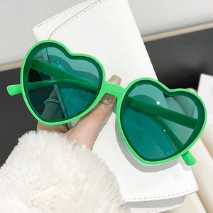 Detail shot of heart-shaped green party sunglasses with translucent dark lenses