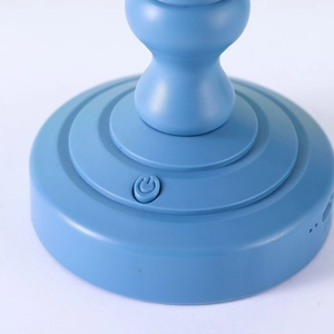 Dettaglio della base della lampada vintage blu con pulsante di accensione su sfondo bianco