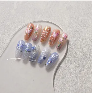 Detail of long coffin nails featuring 3D blue roses and pink butterfly nail art