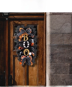 Detail of Halloween BOO door wreath with orange and black ribbons on a wooden door