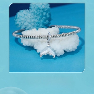 Detail of s925 silver mermaid tail pendant with opal inlay and shell on a blue background