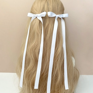 Close-up of white ribbon bow hair clips styled on blonde hair for a balletcore look