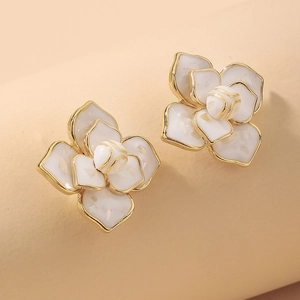 Close-up of elegant camellia earrings with white enamel petals and gold accents