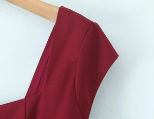 Détail du décolleté carré rouge et de la couture d'épaule sur une robe élégante