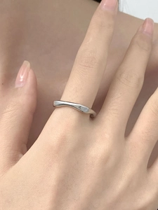 Close-up of minimalist silver wave ring with irregular geometric texture on finger