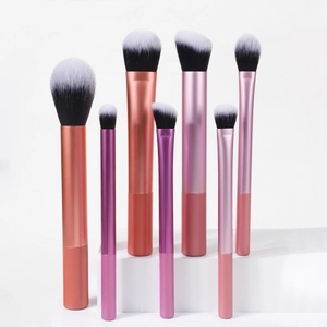 Dettaglio di 7 pennelli da trucco professionali con manici sfumati rosa e viola metallico