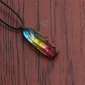 Macro view of wire-wrapped tree of life pendant with rainbow crystal on wood background