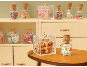Macro view of miniature dollhouse gingerbread candy boxes and glass jars on wooden table