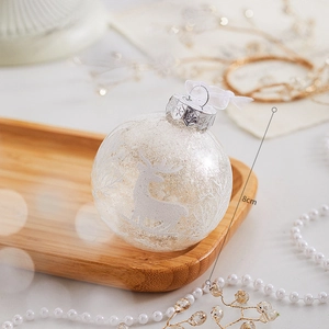 Détail d'une boule de Noël blanc perle de 8cm avec renne doré pailleté et motifs flocons