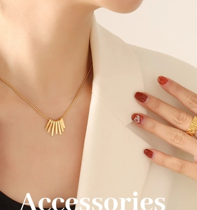 Detail of fan-shaped golden pendant on snake chain with textured gold ring on model