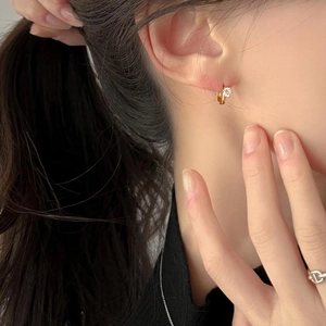 Close-up of a minimalist gold ear cuff featuring a sparkling round cubic zirconia stone