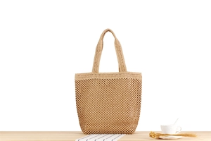 Gros plan détaillé d'un sac cabas tissé beige posé sur une table en bois clair