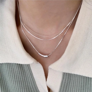 Close-up of triple-layered 925 sterling silver necklace with teardrop pendant on neck