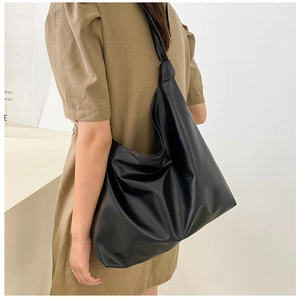 Detailed shoulder view of a large black leather tote bag with soft pleated texture