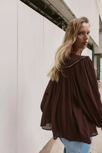 Detail of bohemian dark red blouse showing pleated texture and decorative back stitching