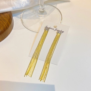 Close-up of golden long tassel earrings with sparkling crystals on jewelry card