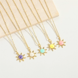Detail of five colorful sunburst pendants with gold chains on a stone display board