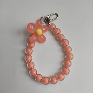 Detail of pink beaded phone strap with acrylic flower charm and silver metal clip