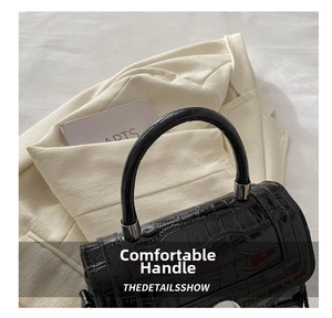 Detail of black crocodile pattern leather handbag with polished silver metal hardware