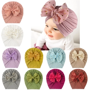 Macro detail of knit baby hats with gold polka dot chiffon bows in various colors