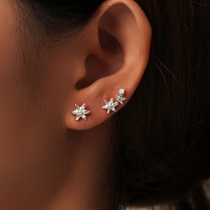 Close-up of s925 silver star earrings with zircons worn on a model's ear