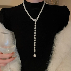 Detailed view of long Y-shaped necklace with leaf pendant and water-drop faux pearl