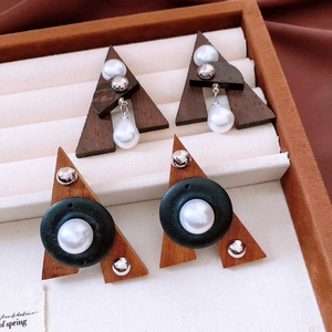 Detailed macro of wooden triangle earrings with pearls in vintage ethnic style