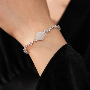 Close-up of a zircon chalcedony bracelet on a wrist featuring a white round center stone