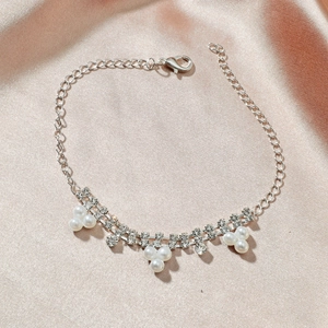 Détail d'une chevillère en strass brillant avec perles sur fond de satin rose