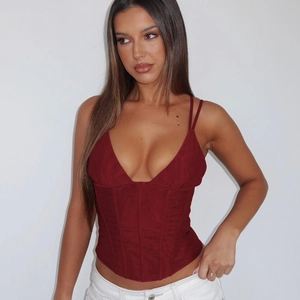 Detail view of a sexy red deep V-neck corset top on a model with a minimalist background