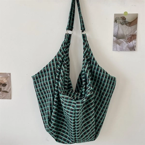 Close-up of green checkered hobo bag with sturdy metal rings and canvas fabric texture