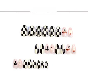Detail view of almond press-on nails with black checkerboard and Halloween moon patterns