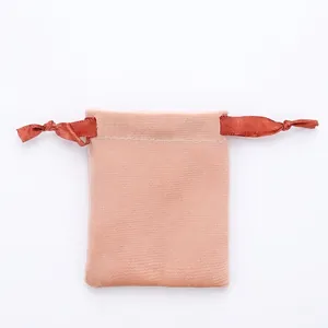 Close-up of a soft pink velvet jewelry drawstring pouch with orange silk ribbons