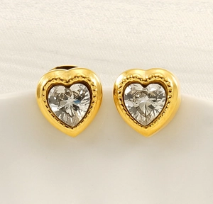 Close-up of gold heart earrings with heart-cut clear zircon and delicate beaded edges