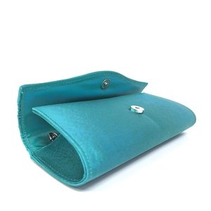 Detail view of the sleek magnetic clasp and silky satin fabric on the lake blue clutch