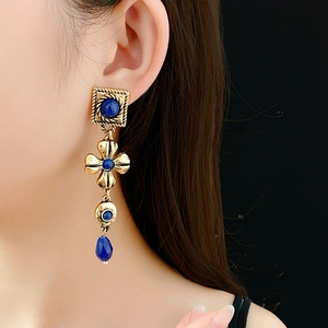 Detail of vintage gold earrings with deep blue stones and tassel design on model