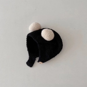Detail of baby winter knit hat with cozy black earflaps and soft off-white faux fur pom-poms