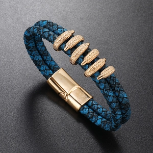 Detail view of blue braided leather bracelet with golden magnetic clasp and metallic charms