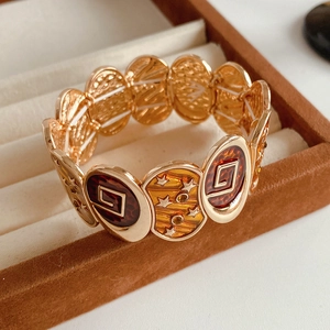 Gros plan d'un bracelet vintage en émail rose doré avec étoile dans un écrin brun