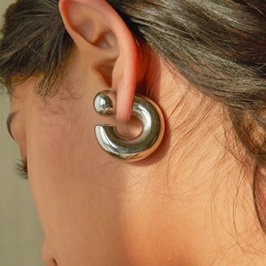 Close-up of chunky silver C-shaped hoop earring in polished stainless steel for women