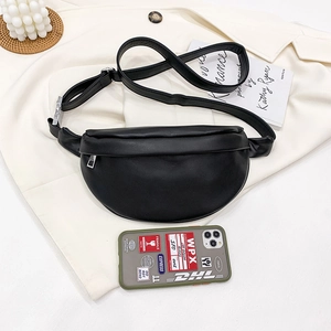 Minimalist black crescent waist bag on beige fabric with modern lifestyle props