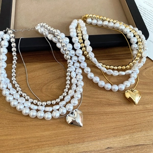 Détail du collier de perles multicouche avec pendentif coeur poli en or et en argent