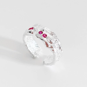 Detail of 925 sterling silver ring with irregular lava texture and three red zircons