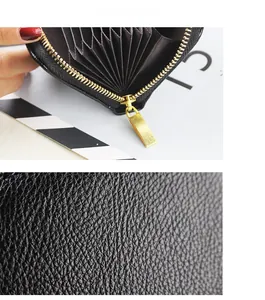 Macro detail of black pebble leather and golden metal zipper on the accordion card holder