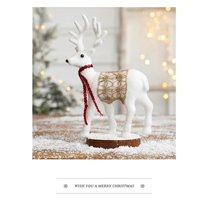 White Christmas reindeer figurine with red bead scarf on a round wooden base