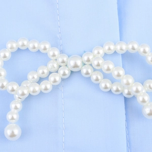 Hellblaue Popeline-Bluse mit elegantem weißem Perlen-Schleifendekor am langen Ärmel