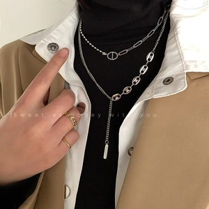 Détail de colliers géométriques superposés avec pendentif anneau sur un mannequin en hiver