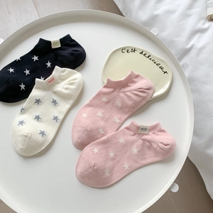 Detail of four cotton star-patterned ankle socks displayed on a white tray